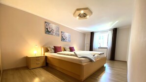 Una camera da letto moderna con un letto in legno, comodini e una lampada a sospensione.