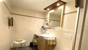 Un bagno compatto con lavandino, specchio, WC e un piccolo sgabello.