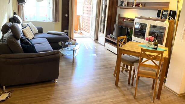 Un soggiorno moderno con un divano, un tavolino in vetro e un'area pranzo con un tavolo e sedie in legno.