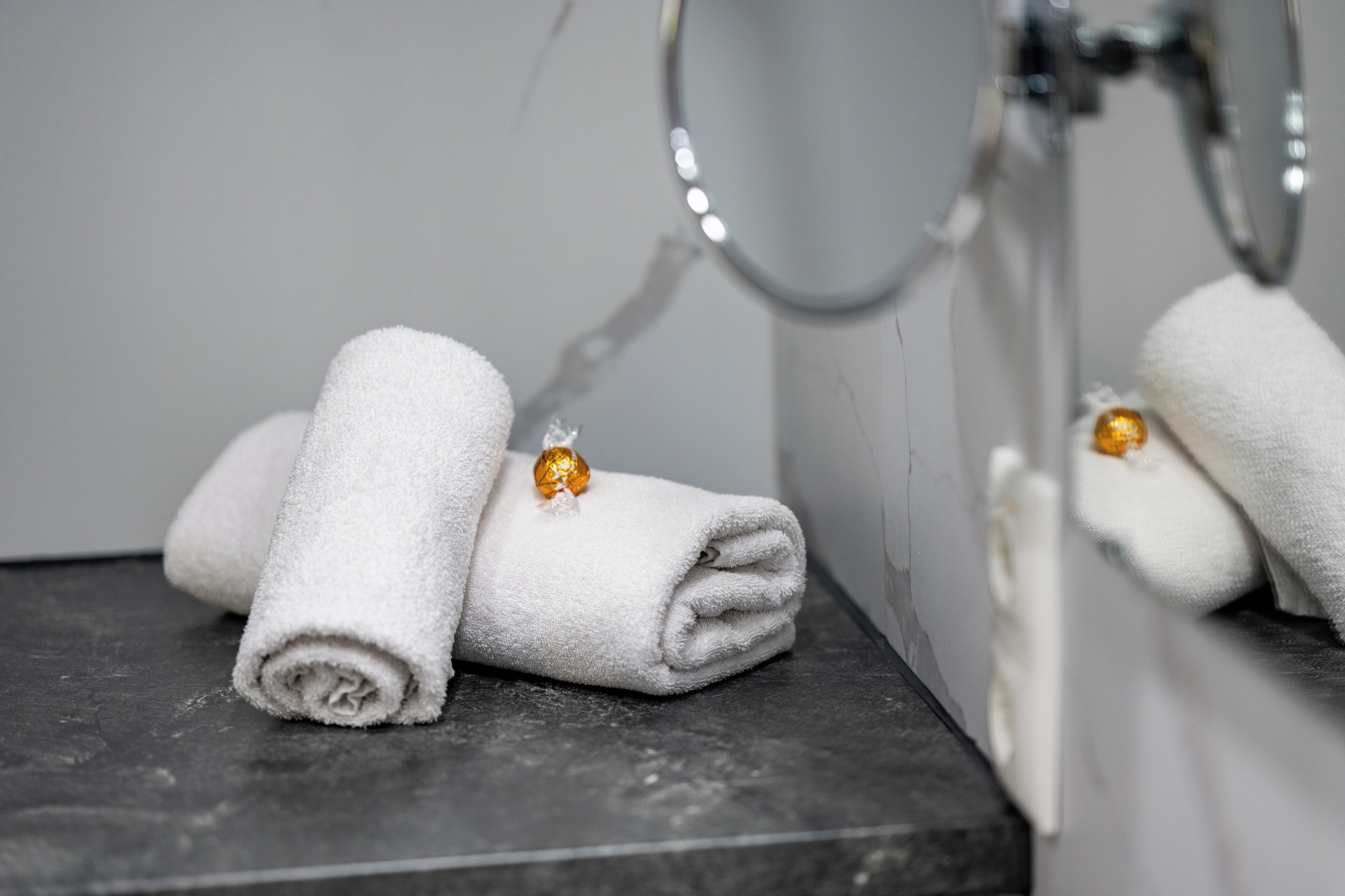 A bathroom with a mirror, two white towels, and a gold-colored object on one of the towels.