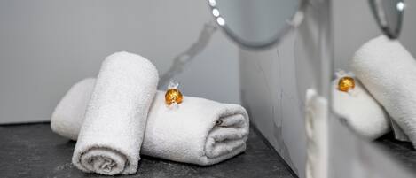 A bathroom with a mirror, two white towels, and a gold-colored object on one of the towels.