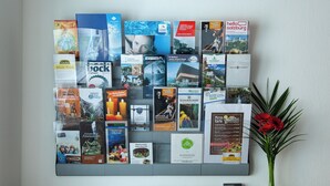 Una bacheca con diverse brochure di viaggio e un vaso con fiori su un tavolo.