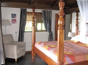 A bedroom with a four-poster bed, a chair, a window with curtains, and a lamp. - Holiday home in the Caribbean with pool & sea view, 10 min. to beach, golf (Castries)