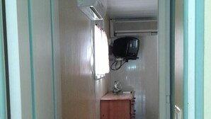 A narrow hallway with a wooden cabinet, a television mounted on the wall, and a tiled floor. - Stunning villa top 10mins beach (Rivière-Pilote)