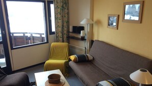 Een knus ingerichte kamer met een bank, een tafeltje, een stoel en een lamp.
