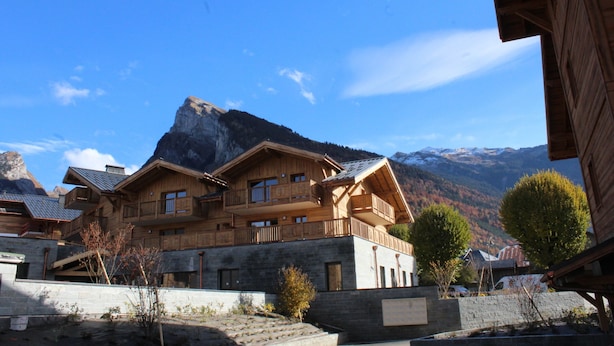 Un chalet en bois doté de balcons, situé dans un cadre montagneux.
