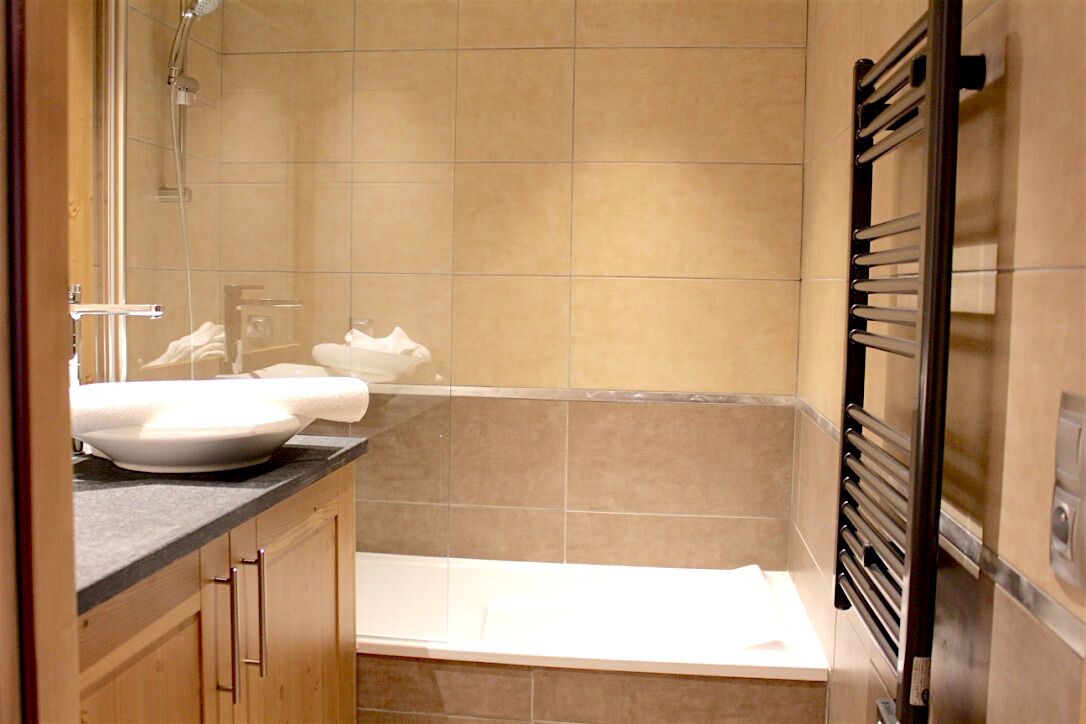 A bathroom with a bathtub, a sink, and a towel rack.