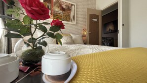 A hotel room with a bed, a vase with a red rose, a white cup, and a yellow textured blanket. - Large, Comfortable, Air-Conditioned Historic House with a Sauna. (Ver-sur-Mer)