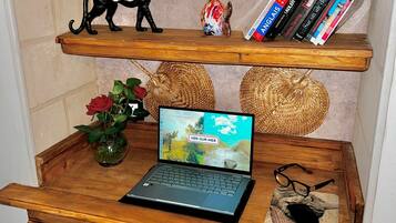 A wooden shelf unit with decorative items, books, a laptop, and a vase with a red rose.