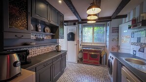 A kitchen with patterned tiles, a stove, a sink, and a refrigerator. - Large, Comfortable, Air-Conditioned Historic House with a Sauna. (Ver-sur-Mer)