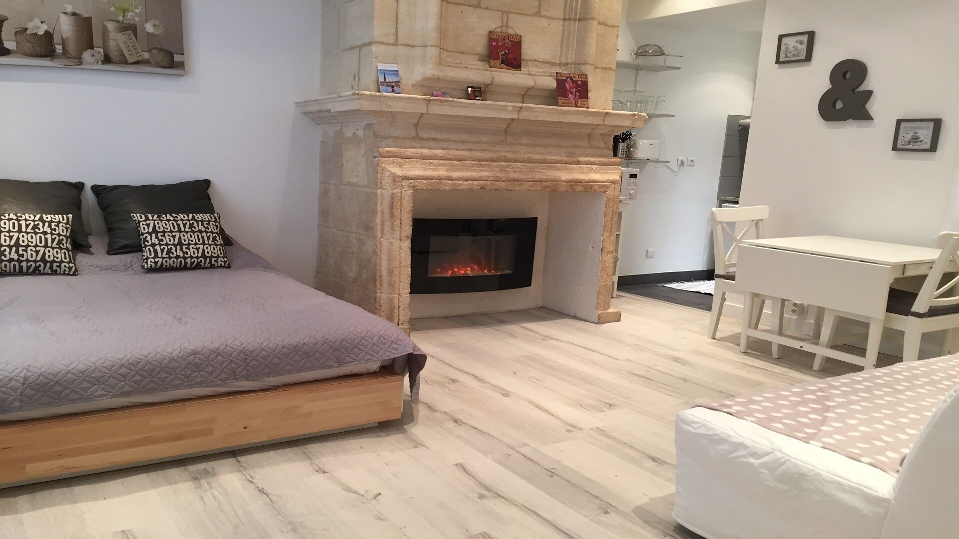A bedroom with a bed, a fireplace, a small table, and a chair.