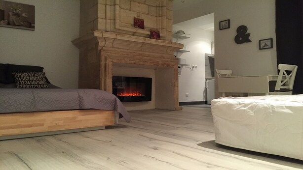 Een slaapkamer met een stenen openhaard, een bed, een stoel en een klein tafeltje.