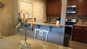 A kitchen with a marble countertop, stainless steel appliances, and wooden cabinets. - Charming Singingwood House (Sacramento)