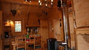 Ein gemütliches Holzhäuschen im Inneren mit Essbereich, Kamin und einer Deckenleuchte.