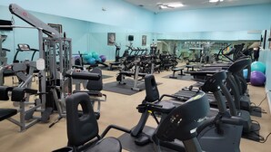 Une salle de sport équipée de divers appareils d’exercice, notamment des tapis de course et des appareils de musculation, et dotée d’un miroir mural.