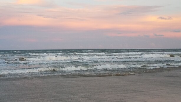 Une plage avec des vagues et un ciel nuageux.