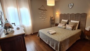 Un dormitorio ordenado con una cama, mesitas de noche, un aparador y un tocador con espejo.