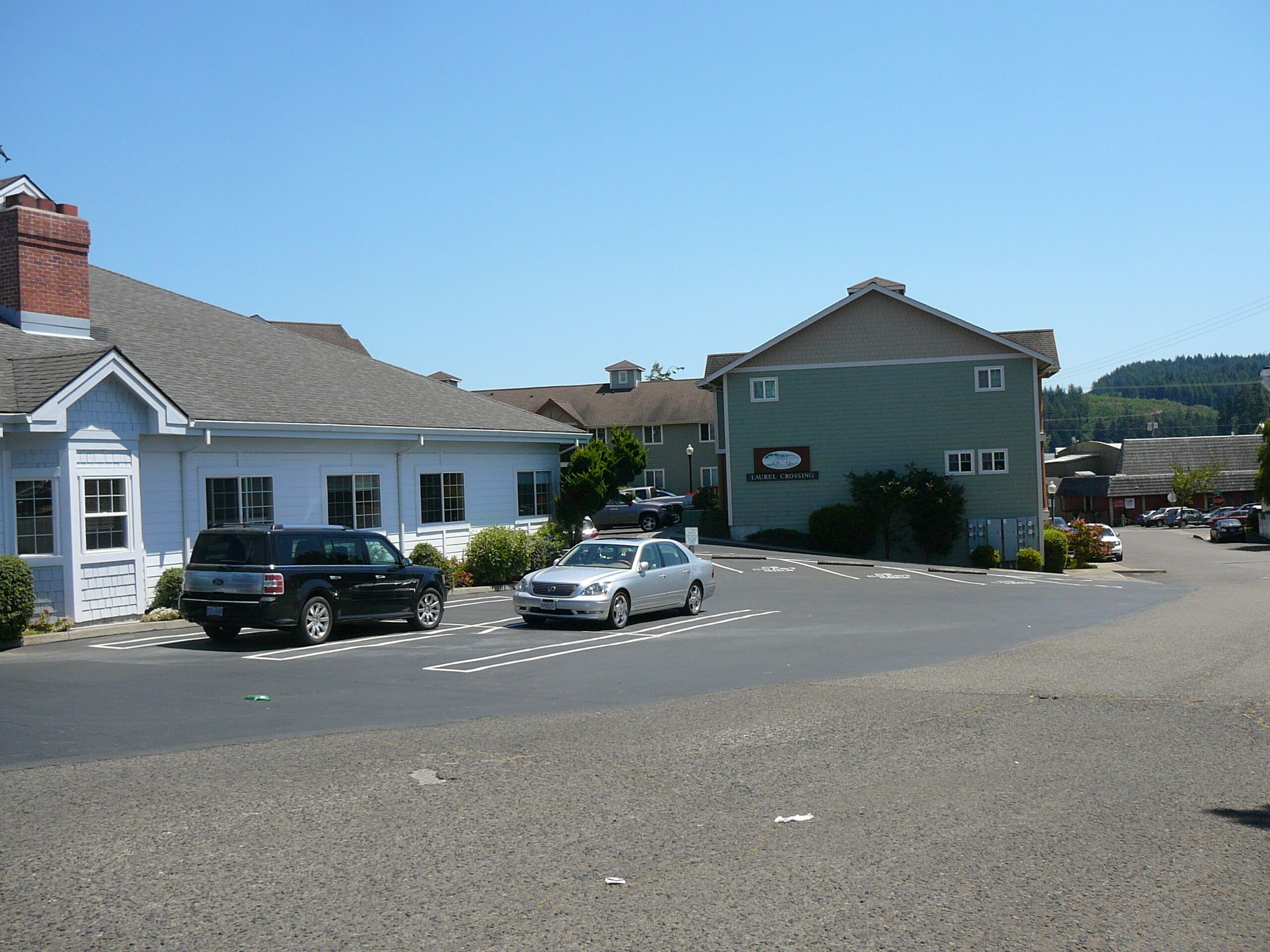 A street view with a building labeled 'LAUREL CROSSING' and a parking lot with cars.