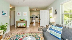 A living room with a gray sofa, a colorful rug, and a view into the kitchen. - The Little Sandy...#1 in Siesta! (Siesta Key)