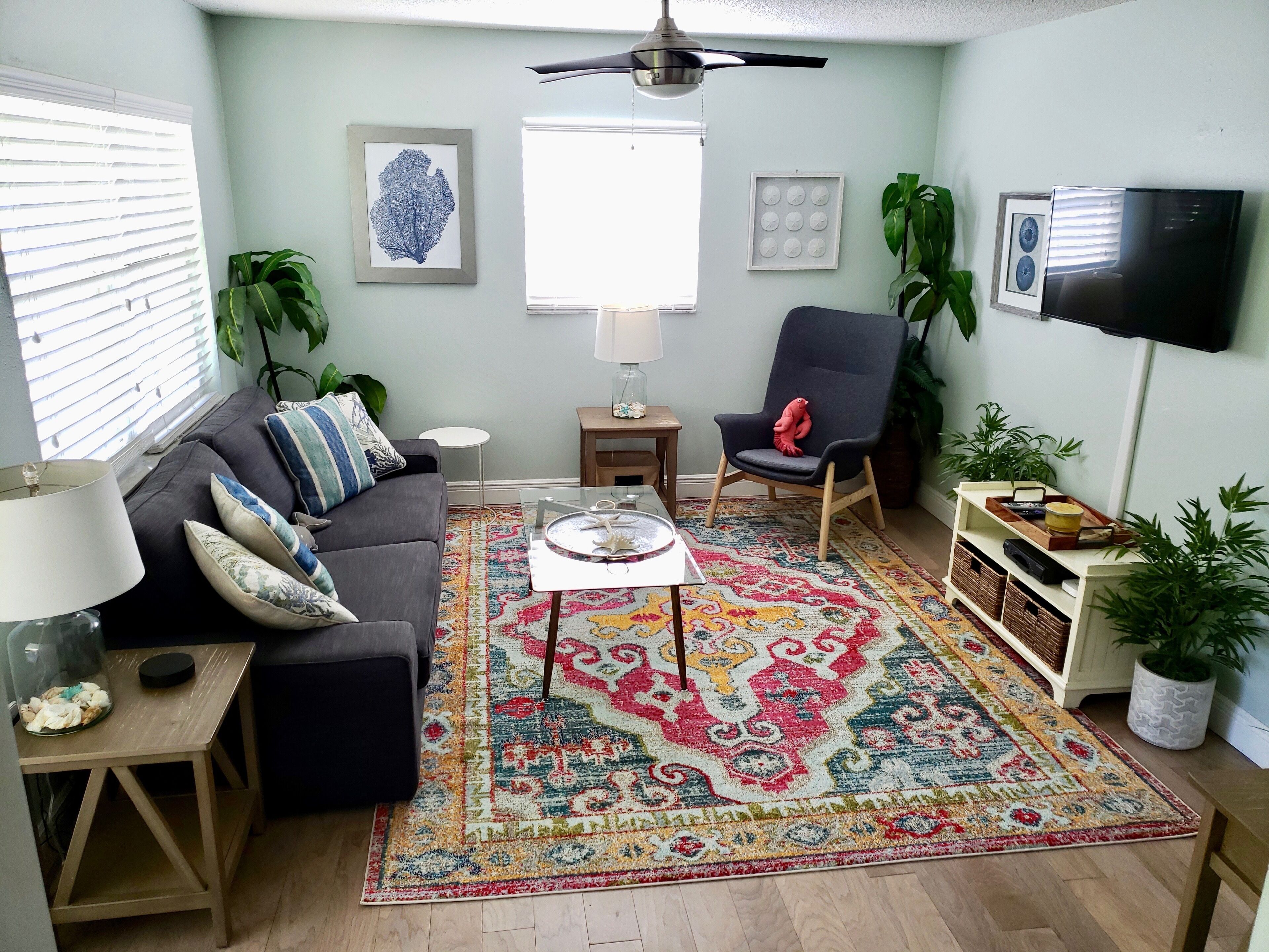 A living room with a sofa, a coffee table, a chair, a TV, and a patterned rug.