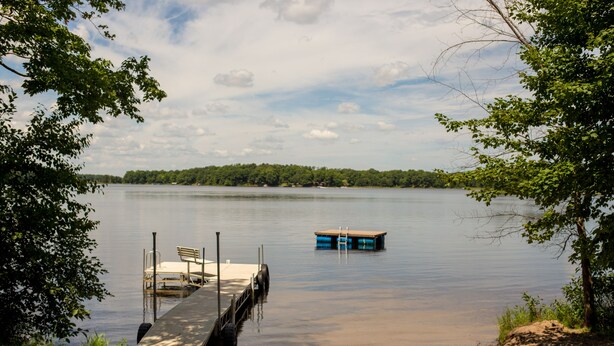 A lakeside dock with a bench and a small boat. - Private - Secluded Lake Home/Sleeps up to 20 people (Deerwood)
