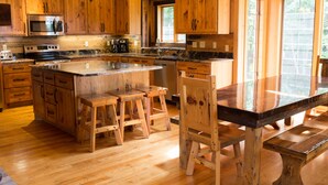 A kitchen with wooden cabinets, a large island with stools, and a built-in oven. - Private - Secluded Lake Home/Sleeps up to 20 people (Deerwood)