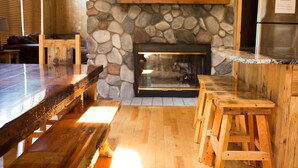 A wooden bar with a stone fireplace, a refrigerator, and a wooden bench. - Private - Secluded Lake Home/Sleeps up to 20 people (Deerwood)
