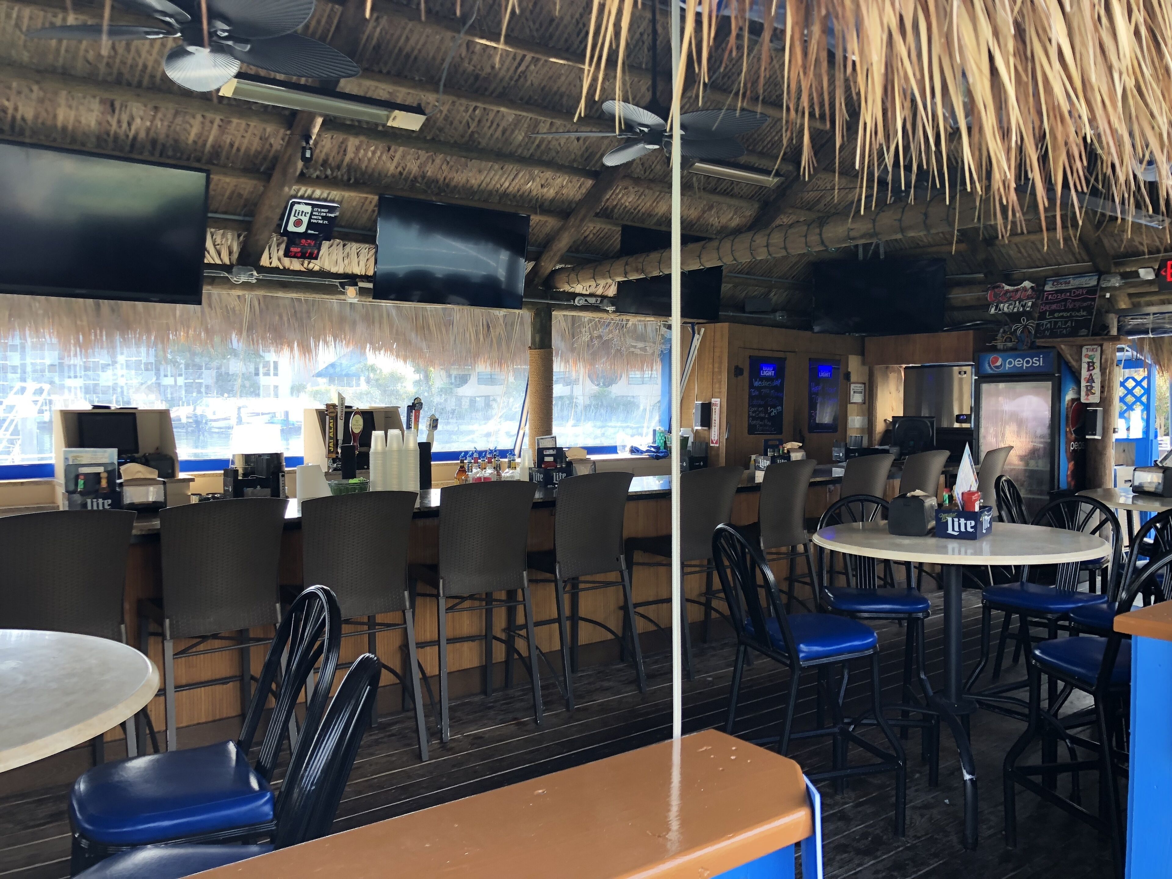 Ein Restaurant mit Strohdach, Bar und einer Sitzordnung.