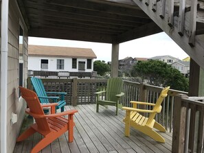 A wooden deck with colorful Adirondack chairs and a covered area.