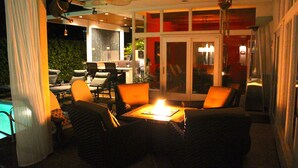 Ein Außenbereich mit Sitzgelegenheiten, einem Tisch, Stühlen, einem Pool und einer Glastür zu einem Innenraum.