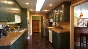 Eine Küche mit dunkelgrünen Schränken, einer Arbeitsplatte aus Granit und einem eingebauten Backofen.
