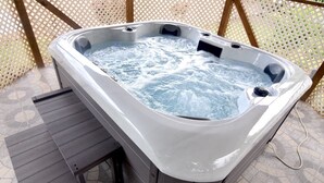 Un bain à remous doté d’une terrasse en bois et d’un sol carrelé.