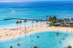 Uma praia com águas turquesa cristalinas, palmeiras e um cais.
