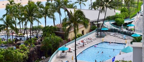 A resort with a large pool, palm trees, and a beach view.