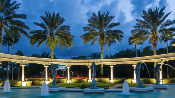 A well-lit outdoor area with palm trees, a bridge, and a pool with fountains. - Family-Friendly House 3 Miles From Disney,  Security Resort,Games Room, Pool spa (Kissimmee)
