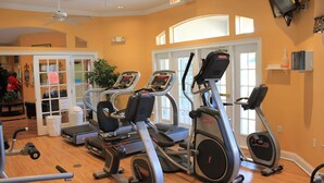 A gym with treadmills, ellipticals, and a ceiling fan. - Family-Friendly House 3 Miles From Disney,  Security Resort,Games Room, Pool spa (Kissimmee)
