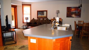 A kitchen with a built-in island, wooden cabinets, a sink, and a dining area with chairs and a table. - Best Location in The Center Village at Copper Mountain! (Copper Mountain)