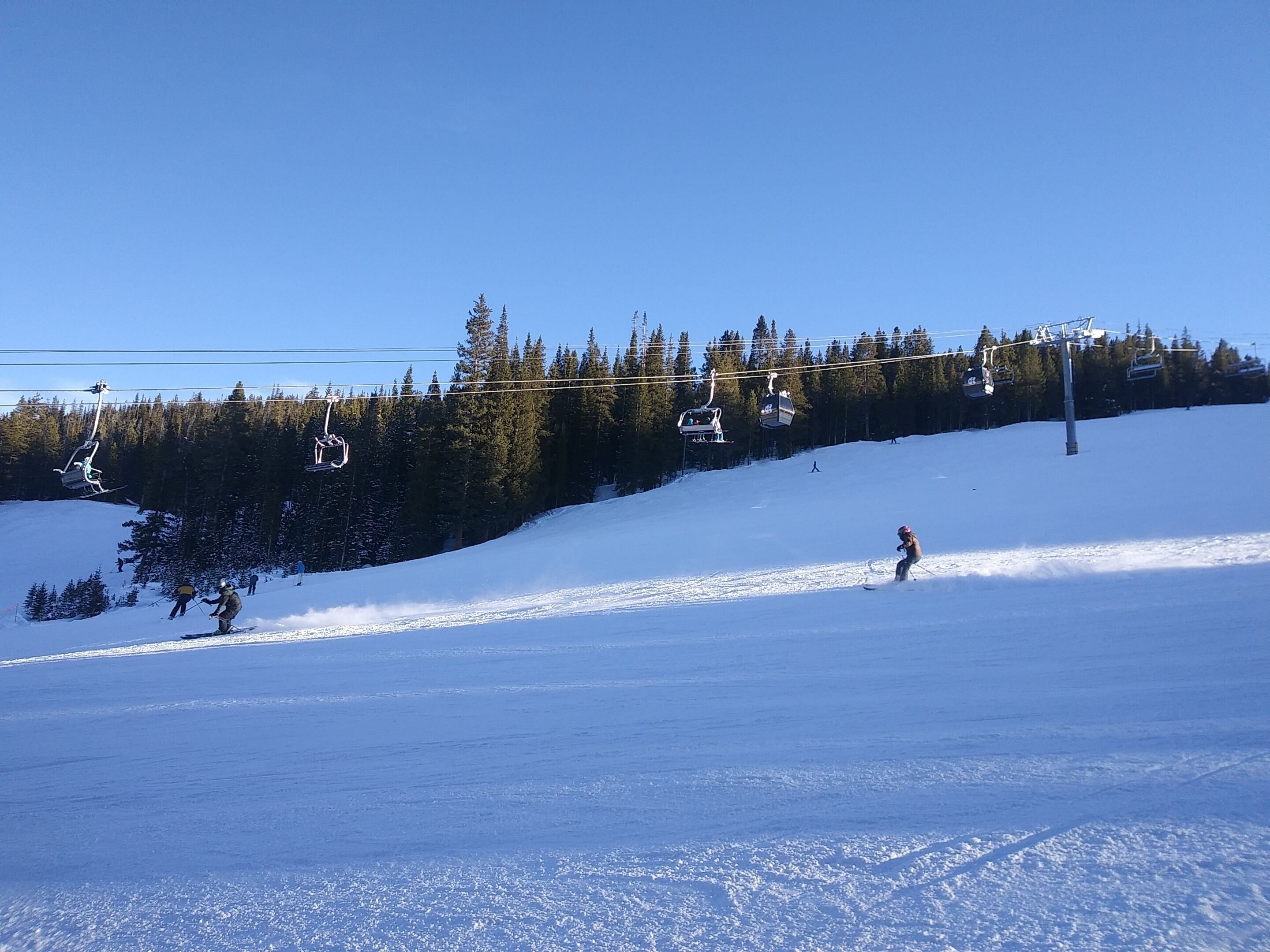 Une piste de ski avec un télésiège et des arbres en arrière-plan.