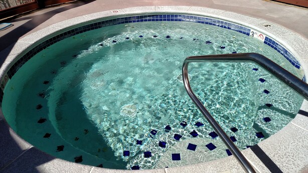 A hot tub with clear water, a metal ladder, and a tiled edge. - Best Location in The Center Village at Copper Mountain! (Copper Mountain)