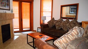 A living room with a fireplace, a sofa, a coffee table, and a lamp. - Best Location in The Center Village at Copper Mountain! (Copper Mountain)