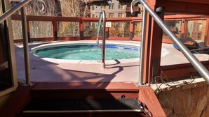 A pool area with a metal railing, a sign indicating pool hours, and a view of buildings in the background. - Best Location in The Center Village at Copper Mountain! (Copper Mountain)