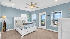 A bedroom with a bed, a ceiling fan, a window with blinds, and a view of the outside. - Amazing View, Gorgeous Beachfront, Huge Deck, Luxury Retreat-Sleeps 14, Starlink (Crystal Beach)