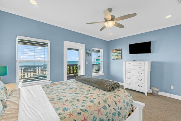 Une chambre à coucher avec un lit, un ventilateur de plafond, une commode et un téléviseur.