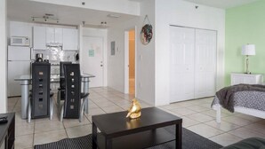 Un apartament modern amb zona de menjador, cuina americana i saló amb llit.
