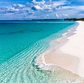 Een strand met helder turquoise water en wit zand.