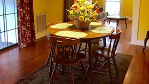 A dining area with a round table, chairs, a chandelier, and a floral centerpiece. - Fully Furnished Two Bedroom Farm House, "The Little House" Has Everything ! (Delight)