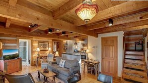 A rustic interior with a wooden dining table, sofas, and a staircase. - Cozy Log Cabin, Mountain views, HOT TUB, & Fire Pit- accepting renters! (Zionville)