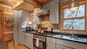 A modern kitchen with stainless steel appliances, wooden cabinetry, and a large window providing natural light. - Cozy Log Cabin, Mountain views, HOT TUB, & Fire Pit- accepting renters! (Zionville)