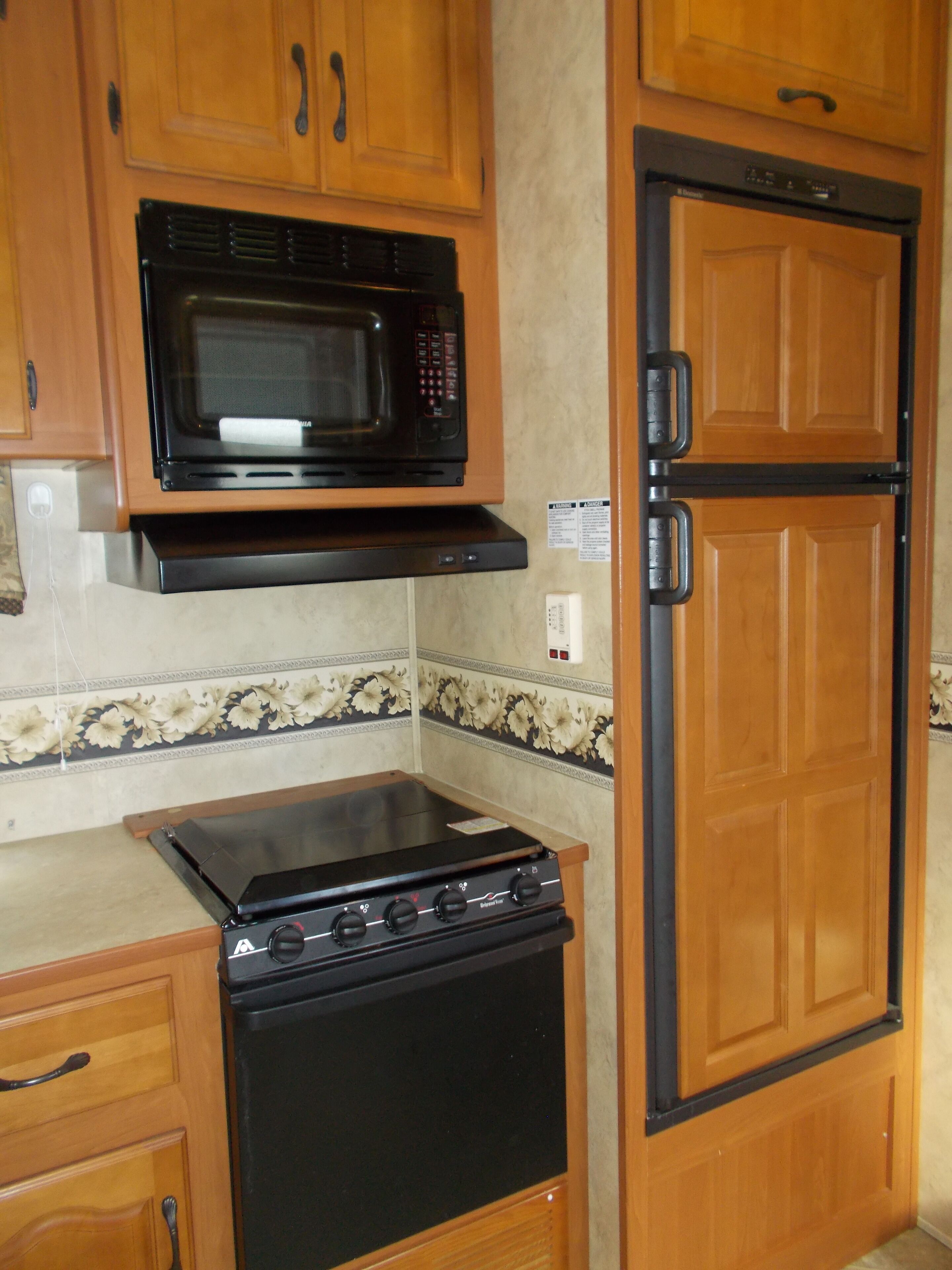 Una cocina compacta equipada con microondas, estufa y refrigerador.