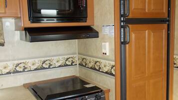 Una cocina compacta equipada con microondas, estufa y refrigerador.